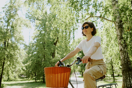 Low angle shot of senior woman enjoying bike walk in local park during warm summer dayの写真素材
