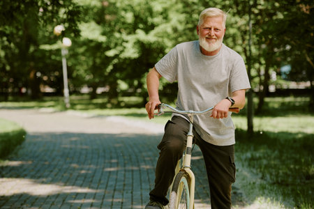 Silver-haired man having break after bike ride, he looking directly at camera and posing for photoの写真素材