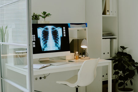 Modern medical office showing desk with x-ray display monitors and various office supplies and plants adding elements of greeneryの写真素材