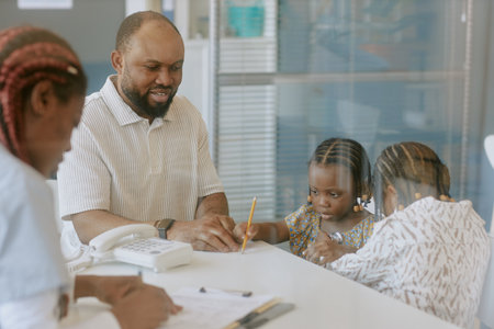 Counselor discussing important matters with parents and two children while seated around office desk. Advisor engaging with family in supportive environmentの写真素材