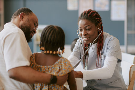 Smiling nurse in scrubs checking young girls health with father, girl wearing patterned dress, father holding daughter, creating warm and caring environmentの写真素材