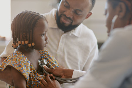 Doctor examining young girl with stethoscope while an adult supervising. Scene inside a healthcare setting capturing gentle interaction and medical careの写真素材