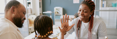 Doctor giving high-five to child during medical consultation as father watches proudly. Doctor smiling and showing support for childs achievement in healthcare settingの写真素材