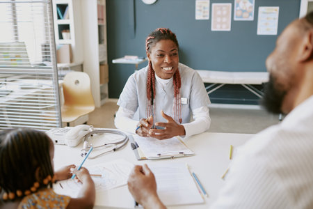 Friendly nurse engaging with patient and family members, taking notes and explaining procedures in medical consultation room, fostering a warm and caring environmentの写真素材