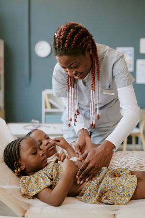 Nurse treating young children lying on medical table. Focus on administering care with young girl in...