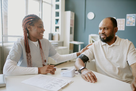 Nurse smiling while assisting patient during medical consultation in clinical setting involving trust and care between healthcare professional and patientの写真素材