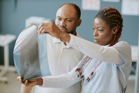 Medical professionals engaging in careful analysis of x-ray images, demonstrating collaborative approach in medical diagnostics in clinical environment focusing on patient careの写真素材