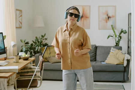 Brunette woman with disability wearing turquoise headphones and listening to music while dancing aloneの写真素材