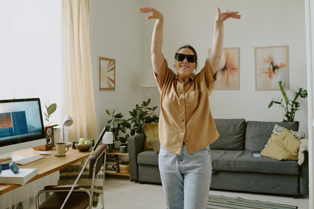 Blind woman smiling widely and dancing while hanging out alone at homeの写真素材
