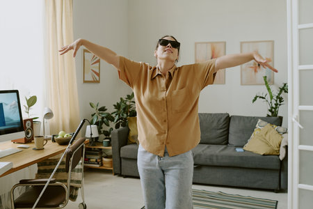 Young woman with disability dancing in room while enjoying free timeの写真素材