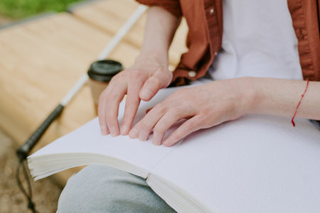 High angle shot of unrecognizable male hands touching embossed page of book in parkの写真素材