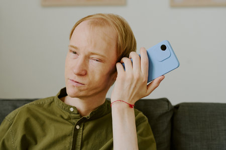 Medium close up of man with disability using his smartphone to listen to friends voice messageの写真素材