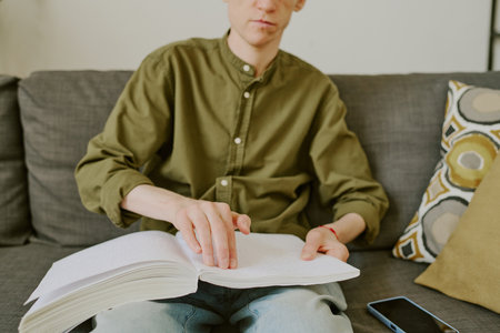 Medium close up of Braille book on knees of unrecognizable man with disabilityの写真素材