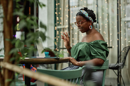 African American female cafe visitor having video call while resting in eco cafeの写真素材