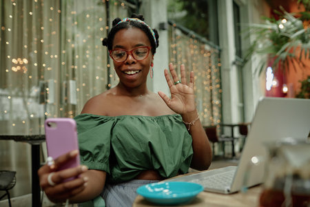 Happy African American female blogger making story while having breakfast in cafeの写真素材