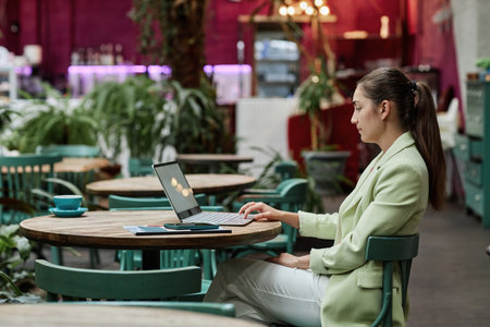 Side view shot of young Caucasian businesswoman working in eco cafeの写真素材