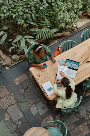 Vertical top down shot of two successful businesswomen discussing documents in cafeの写真素材