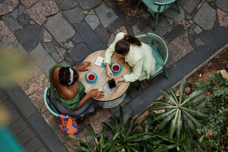 Top down shot of two biracial friends discussing new startup in eco cafeの写真素材