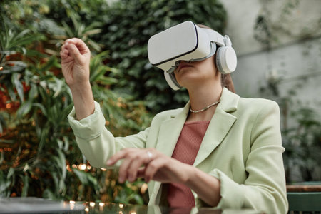 Low angle shot of young woman enjoying VR game while resting in eco cafeの写真素材
