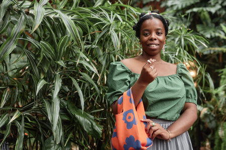 Portrait of young African American woman demonstrating new orange bag