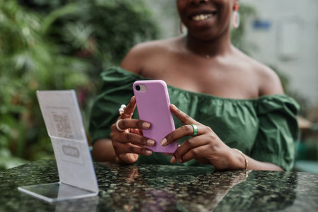 Unrecognizable jolly woman using smartphone to open online menu in modern eco cafeの写真素材
