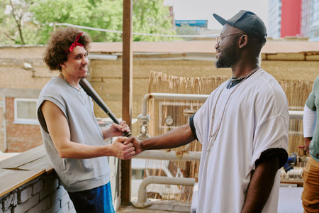 Curly haired man leaning on bricks while greeting his buddy in backyardの写真素材