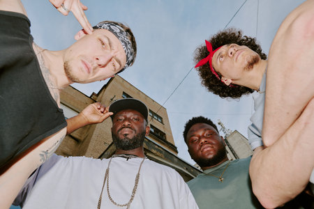 Low angle shot of biracial bad boy band dressed in street style clothes looking at camera
