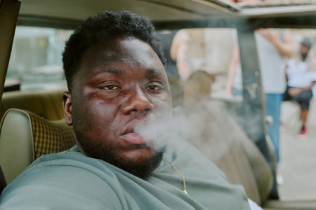 Rough man sitting in car and smoking, he looking directly at cameraの写真素材