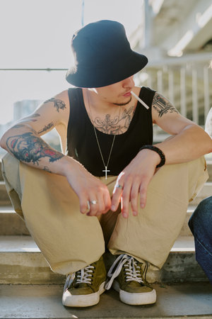 Unrecognizable man sitting on stairs and holding cigarette in mouthの写真素材