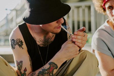 Unrecognizable man wearing jet black panama lighting cigarette while partying with friendの写真素材