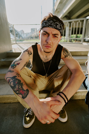 Young brutal rough man sitting on stairs and looking at cameraの写真素材