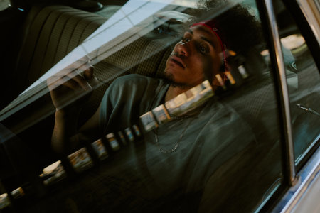 Curly haired man looking at lit cigarette while sitting in backseat carの写真素材