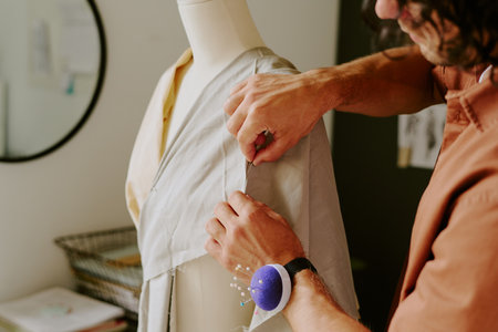 Unrecognizable tailor using needle to do dart on gray cotton fabricの写真素材