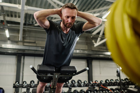 Focused man dressed in sportswear doing hyperextension in gymの写真素材