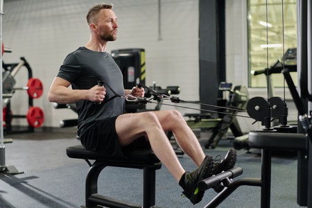 Professional middle aged athlete using horizontal pull machine to improve arm strengthの写真素材