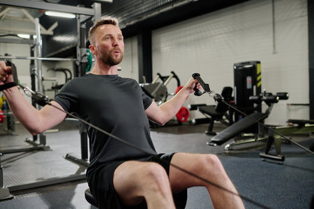 Bodybuilder having heavy workout in gym, he using horizontal pull machineの写真素材