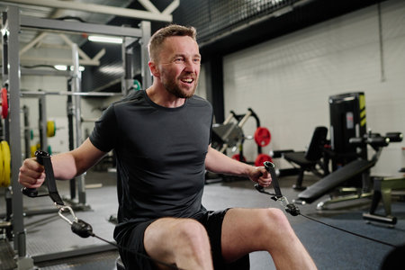 Professional bodybuilder using weight machine to improve muscleの写真素材