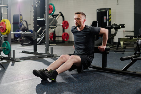 Toned Caucasian man doing reverse push ups in fully equipped gymsの写真素材