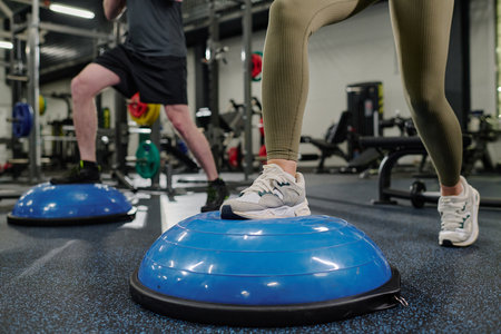 Muscular female and male legs on half-ball during HIIT training on ballの写真素材