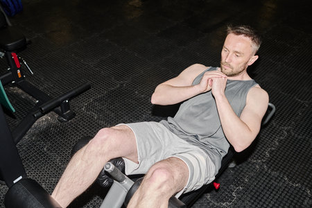 High angle shot of Caucasian man illuminated with flash doing crunches before intense workout
