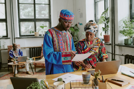 African American coworkers discussing final report while their colleague working in backgroundの写真素材
