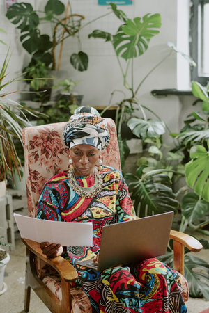 African American businesswoman reading report and taking notes on laptopの写真素材