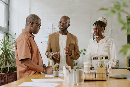 Serious African American boss having meeting with his subordinates in modern light officeの写真素材