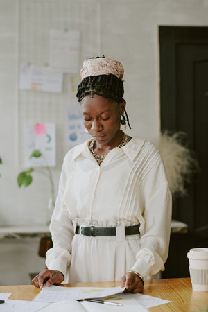 Vertical shot of African American worker dressed in smart clothes reading report in officeの写真素材