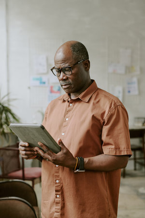 Vertical shot of African American businessman using huge tablet in officeの写真素材