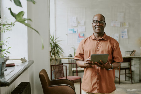 Portrait of smiling African American businessman posing for portrait and holding tablet in handsの写真素材