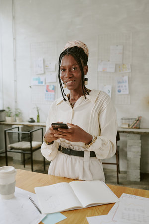 Portrait of smiling African American businesswoman with smartphone in handsの写真素材