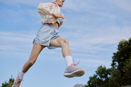 Low angle shot of toned mature unrecognizable woman running in parkの写真素材