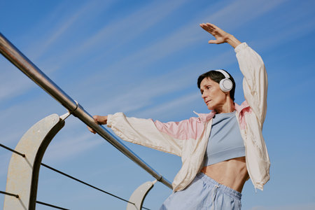 Low angle shot of senior sporty woman stretching while resting on waterfrontの写真素材