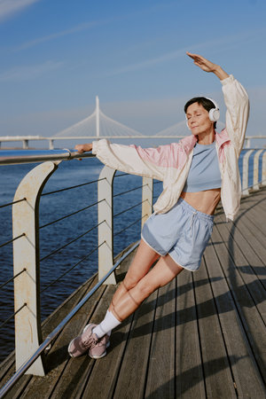 Vertical shot of relaxed woman stretching whole body on waterfrontの写真素材